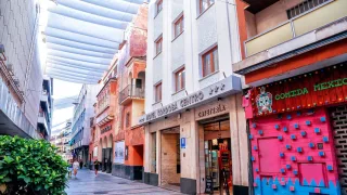 Fachada de hotel con cartel Hotel Córdoba Centro y cafetería visible en una calle peatonal con toldo blanco y locales comerciales a los costados