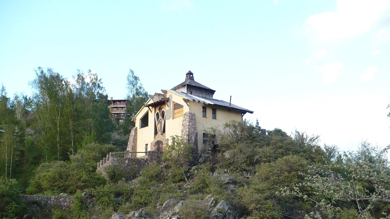 Casa de dos plantas sobre una colina rocosa con vegetación, en La Cumbrecita