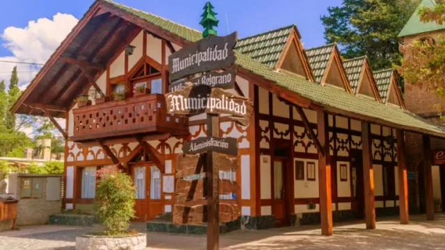 Edificio de la municipalidad con arquitectura alpina, balcón de madera y cartel indicativo en primer plano