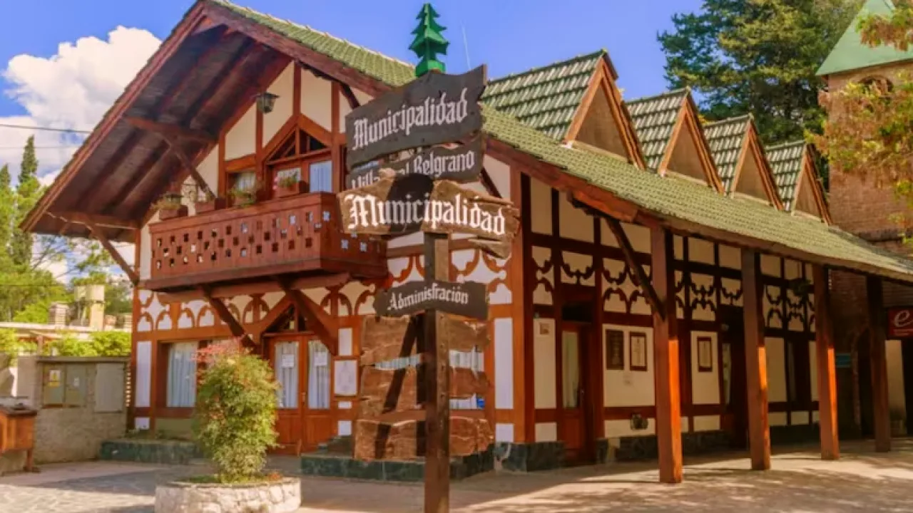 Edificio de la municipalidad con arquitectura alpina, balcón de madera y cartel indicativo en primer plano