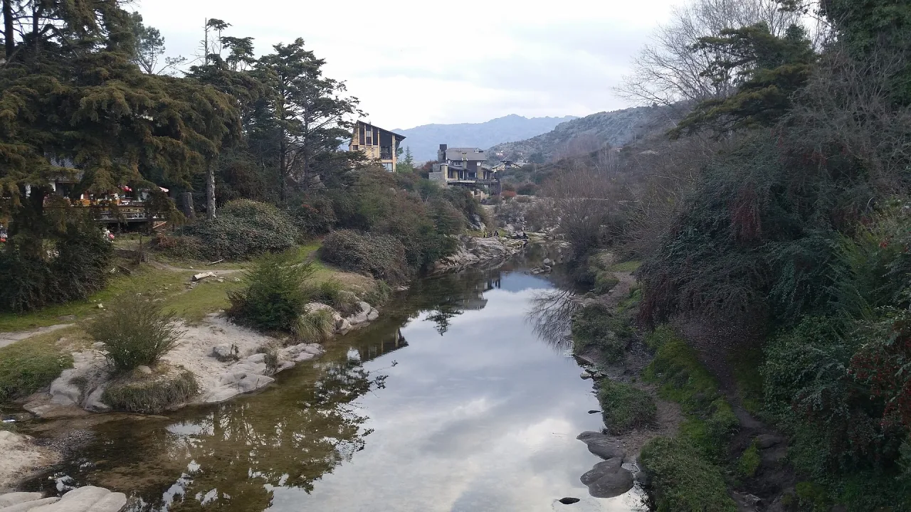 Arroyo de aguas calmas entre árboles y piedras en La Cumbrecita