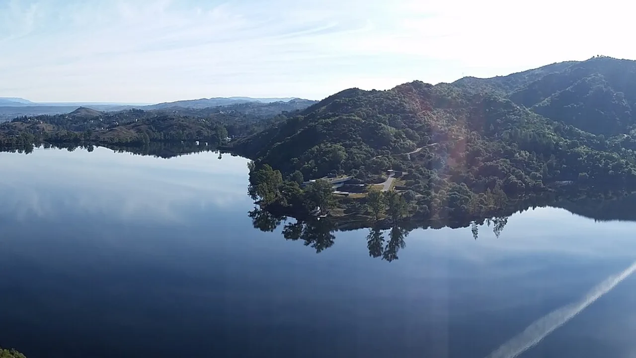 Cerros verdes reflejados en el agua quieta del dique Los Molinos