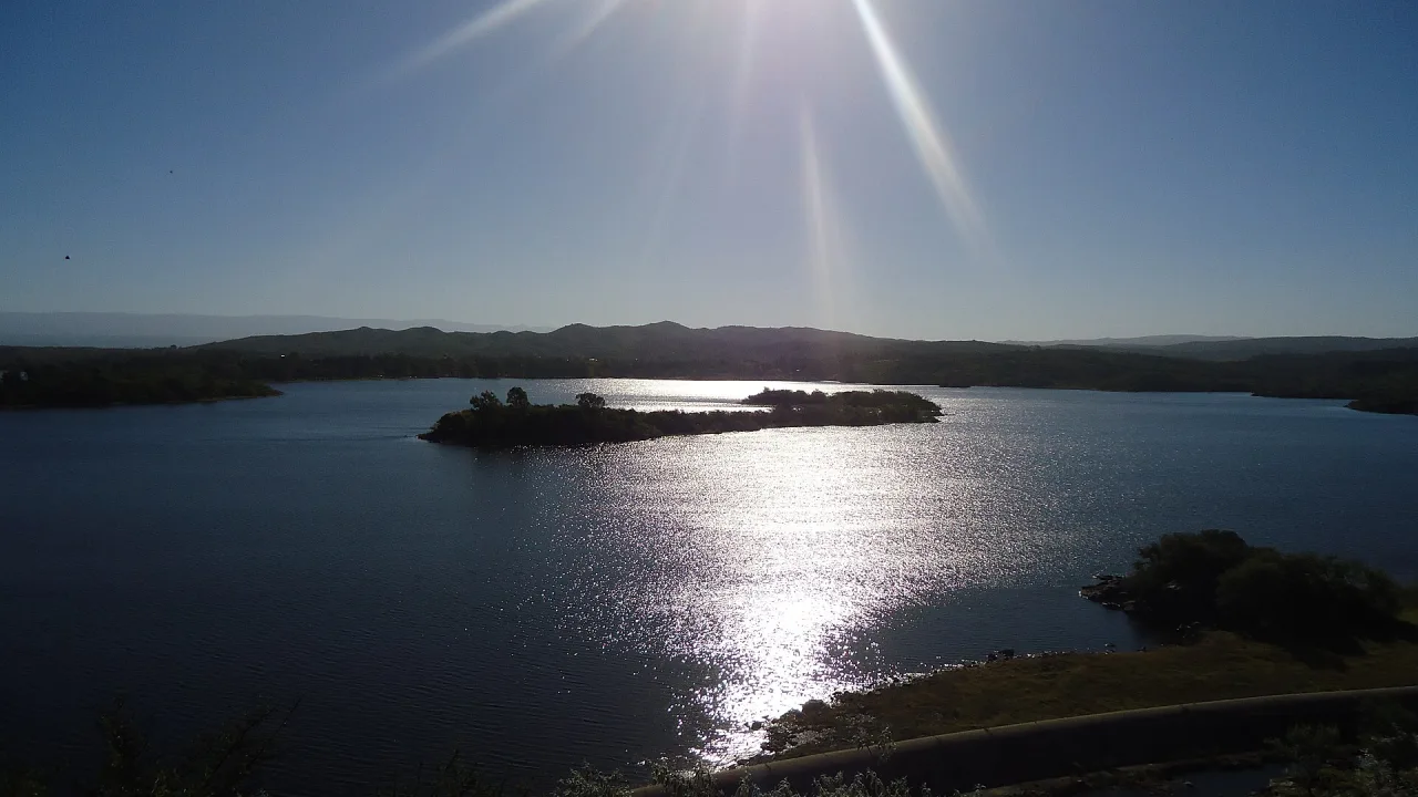 El sol se refleja en el lago del embalse Río Tercero, con una isla en el centro