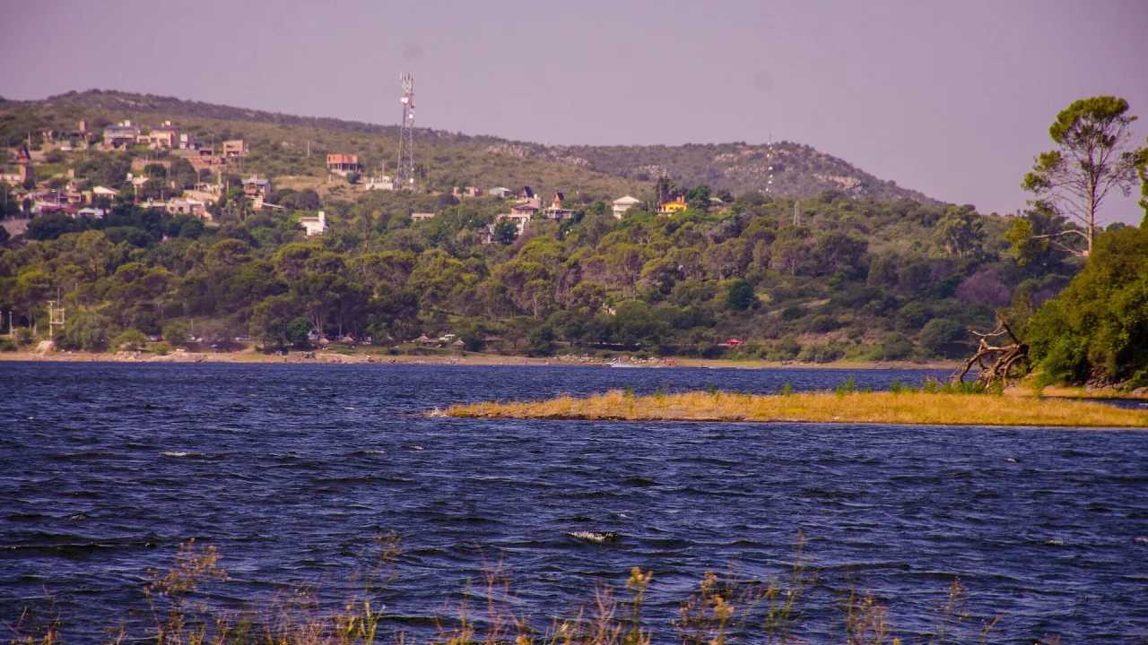 Lago de Embalse con casas entre la vegetación de la costa